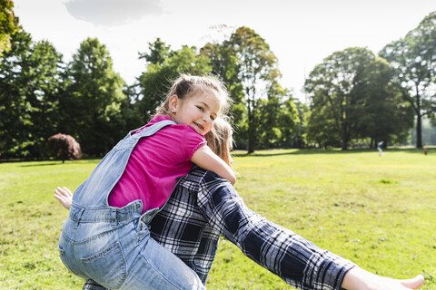 Happy girl on mother's back in a park stock photo