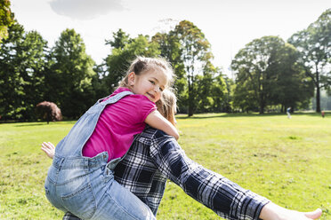 Happy girl on mother's back in a park - UUF13788