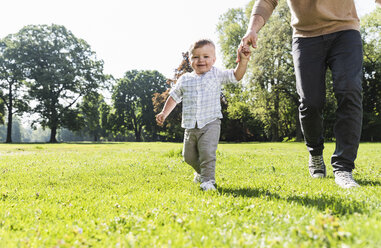 Father walking hand in hand with son in a park - UUF13795