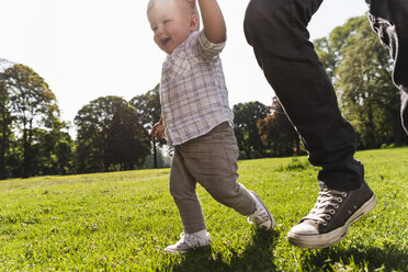 Vater geht Hand in Hand mit seinem Sohn in einem Park spazieren - UUF13796