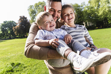 Glücklicher Vater mit Kindern in einem Park - UUF13798