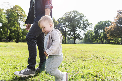 Vater geht Hand in Hand mit seinem Sohn in einem Park spazieren - UUF13804