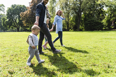 Happy family walking hand in hand in a park - UUF13812