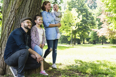 Happy family under a tree in a park - UUF13814
