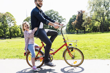 Happy father riding bicycle with daughter in a park - UUF13817