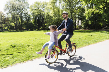 Happy father riding bicycle with daughter in a park - UUF13818