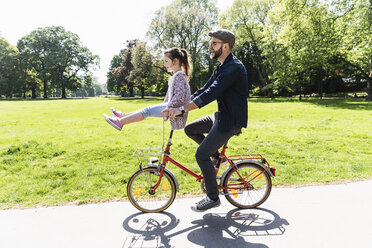 Glücklicher Vater auf dem Fahrrad mit Tochter auf dem Lenker sitzend in einem Park - UUF13820