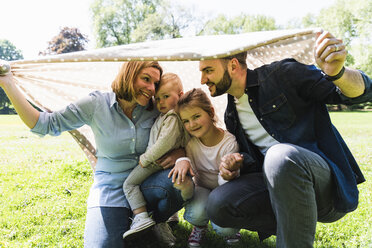 Glückliche Familie unter einer Decke in einem Park - UUF13823