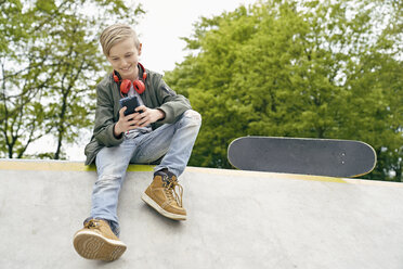 Junge mit Kopfhörern im Skatepark, der sein Smartphone benutzt - PDF01635