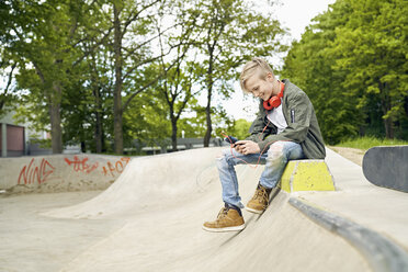 Junge mit Kopfhörern im Skatepark, der sein Smartphone benutzt - PDF01638