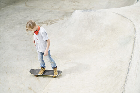 Junge mit Kopfhörern auf dem Skateboard, Skateboard fahren, lizenzfreies Stockfoto