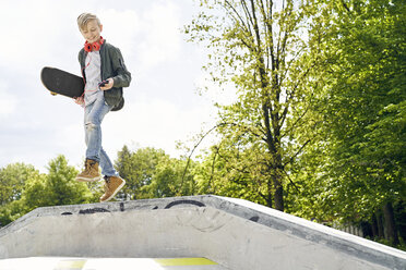 Junge mit Kopfhörern und Smartphone springt von der Rampe im Skatepark - PDF01641