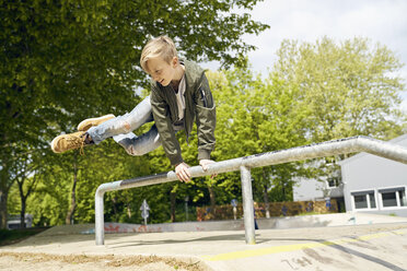 Boy jumping over railing in skatepark - PDF01644