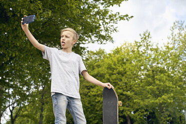 Boy with skateboard taking selfies with smartphone - PDF01645