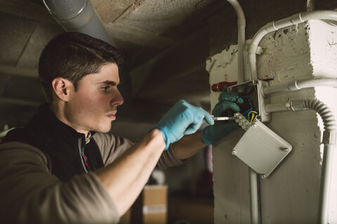 Mann bei Arbeiten an einer elektrischen Anlage, lizenzfreies Stockfoto