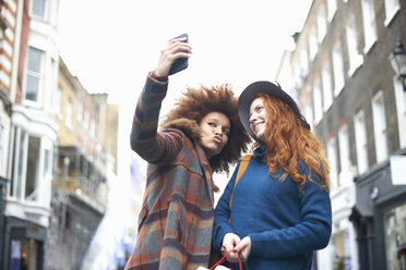 Zwei junge Frauen auf der Straße, die ein Selfie mit ihrem Smartphone machen, Tiefblick - CUF09283