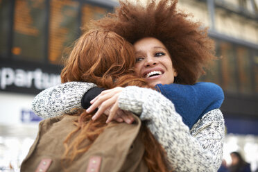 Two young women hugging at train station - CUF09288