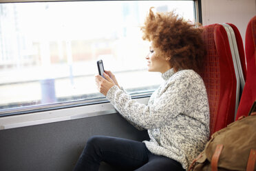 Woman taking photo with mobile phone from train, London - CUF09294