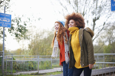 Friends on railway station looking away smiling - CUF09301