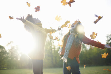 Friends throwing autumn leaves in air - CUF09311