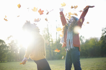 Friends throwing autumn leaves in air - CUF09312