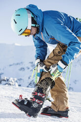 Älterer Mann in Skikleidung, der Skischuhe anzieht - CUF09314