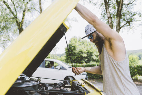 Junger männlicher Hipster beim Anheben der Motorhaube auf einer Autofahrt, Como, Lombardei, Italien - CUF09343