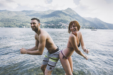 Portrait of couple in swimwear buttock to buttock in Lake Como, Lombardy, Italy - CUF09356