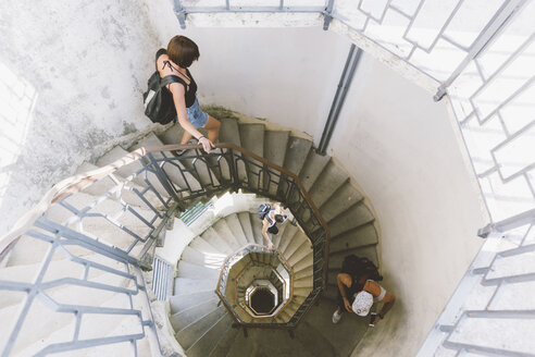 Hochformatige Ansicht von drei jungen Erwachsenen, die eine Wendeltreppe hinuntergehen, Como, Lombardei, Italien - CUF09357