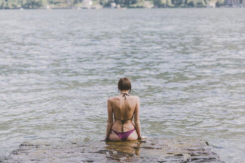Rückansicht einer jungen Frau im Bikini mit Blick auf den Comer See, Lombardei, Italien - CUF09358