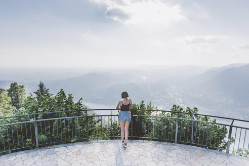 Rückansicht einer jungen Frau auf einer Aussichtsplattform mit Blick auf den Comer See, Lombardei, Italien - CUF09359