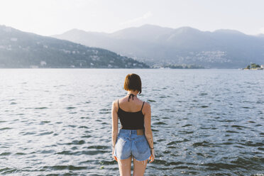 Rear view of young woman on waterfront looking out at Lake Como, Lombardy, Italy - CUF09360