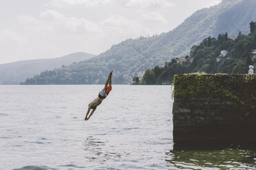 Young male swimmer diving from pier, Lake Como, Lombardy, Italy - CUF09368