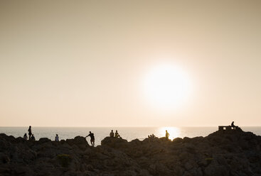 Silhouette of people on rocks at sunset, Ciutadella, Menorca, Spain - CUF09428