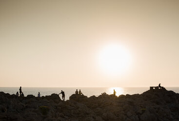 Silhouette von Menschen auf Felsen bei Sonnenuntergang, Ciutadella, Menorca, Spanien - CUF09428