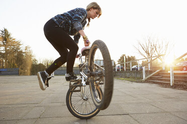 Weibliche BMX-Fahrerin macht BMX-Trick im Park - CUF09575