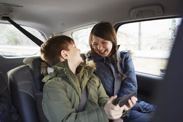 Junge und Schwester lachen auf dem Rücksitz eines Autos - CUF09582