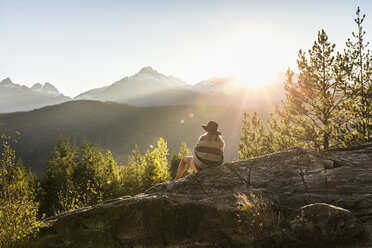 Woman sitting on rocks, looking at view, rear view, Squamish, British Columbia, Canada - CUF09607