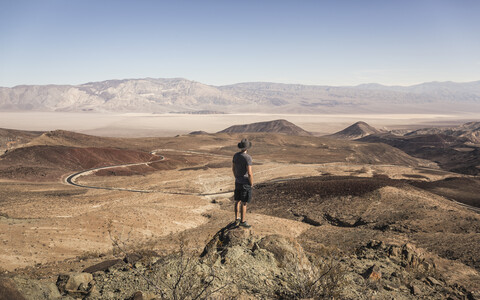 Mann auf einem Felsen mit Blick auf den Death Valley National Park, Kalifornien, USA, lizenzfreies Stockfoto