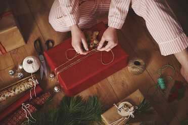 Woman wrapping christmas gift with twine - CUF09626