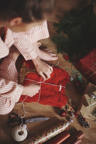 Frau wickelt Weihnachtsgeschenk mit Schnur, lizenzfreies Stockfoto