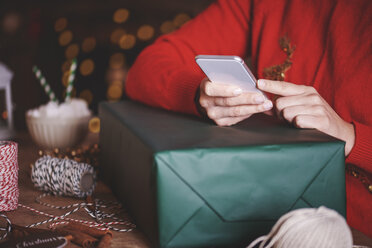 Woman with christmas present using smartphone - CUF09631