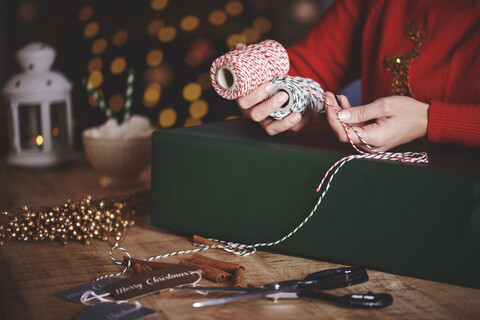 Frau wickelt Weihnachtsgeschenk mit Schnur, lizenzfreies Stockfoto