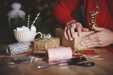 Frau wickelt Weihnachtsgeschenk ein - CUF09633