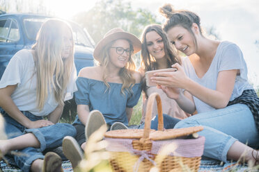 Freunde beim Picknick mit Blick auf Smartphone lächelnd, Firenze, Toskana, Italien, Europa - CUF09654