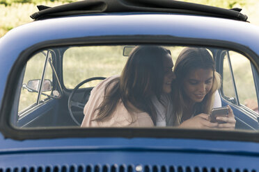 Friends in vintage car looking at smartphone smiling, Firenze, Toscana, Italy, Europe - CUF09668