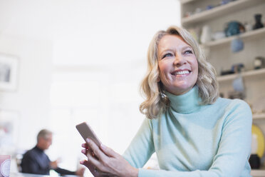 Lächelnde, selbstbewusste reife Frau, die ein Smartphone benutzt - HOXF03538