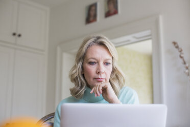 Fokussierte reife Freiberuflerin, die zu Hause am Laptop arbeitet - HOXF03540