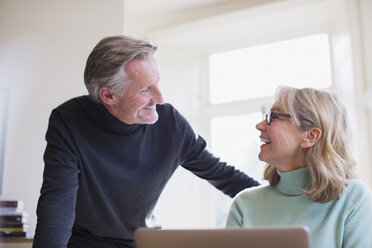 Smiling mature couple talking at laptop - HOXF03541