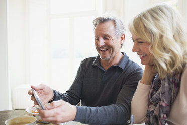 Lächelndes reifes Paar benutzt ein Smartphone - HOXF03549